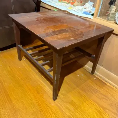 Sale Photo Thumbnail #127: Vintage dark wood end table featuring a slatted lower display shelf, tapered legs, and visible surface wear to the top finish.