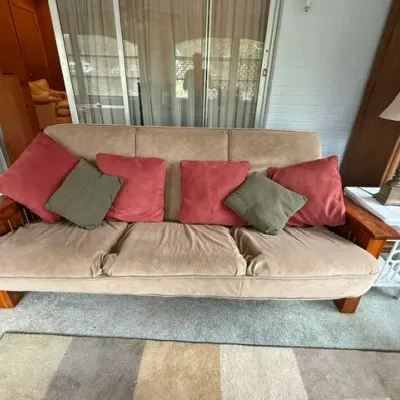 Sale Photo Thumbnail #178: Rustic wooden frame sofa with tan microfiber upholstery and decorative throw pillows, shown in a sunroom setting.