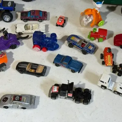 Sale Photo Thumbnail #422: Collection of vintage toy cars, trucks, and novelty vehicles, including die-cast and plastic models showing varied play wear.