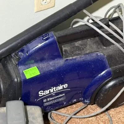 Sale Photo Thumbnail #322: Sanitaire by Electrolux Professional blue canister vacuum cleaner with hose and power cord attached.