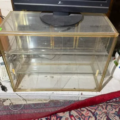 Sale Photo Thumbnail #261: Vintage brass-framed glass display case featuring sliding rear doors and multiple inner glass shelves, shown supporting a monitor.