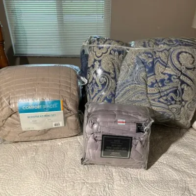 Sale Photo Thumbnail #153: Collection of packaged bedding items including a Comfort Spaces bedspread mini set, a king sheet set, and a blue and beige paisley comforter set.