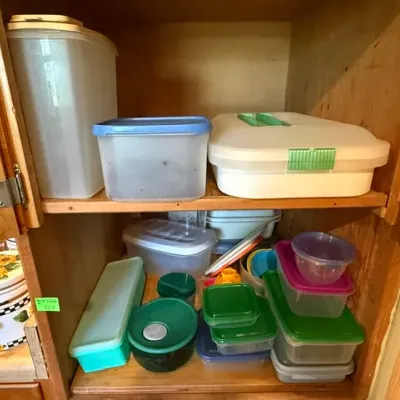 Sale Photo Thumbnail #319: Assorted vintage plastic food storage containers and Tupperware stored inside a wooden kitchen cabinet shelf.