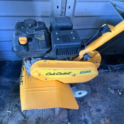 Sale Photo Thumbnail #280: Cub Cadet FT24 front-tine garden tiller with a gas engine, showing light wear and dirt consistent with use.