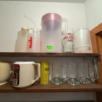 Sale Photo Thumbnail #275: Collection of kitchenware and glassware on wooden shelves, including a Pur water pitcher, a World's Greatest Dad glass mug, clear beer mugs, and plastic pitchers.