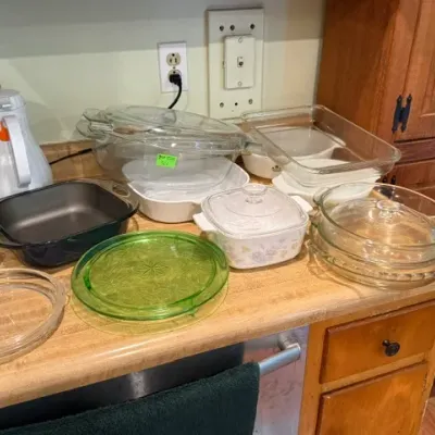 Sale Photo Thumbnail #313: Collection of vintage kitchenware, including CorningWare casserole dishes, Pyrex clear glass baking pans, and green depression glass plates.