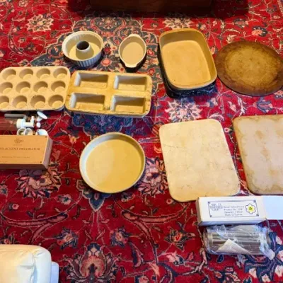Sale Photo Thumbnail #377: Collection of Pampered Chef stoneware bakeware and kitchen tools, including baking stones, loaf pans, a muffin pan, and a cake decorator set.
