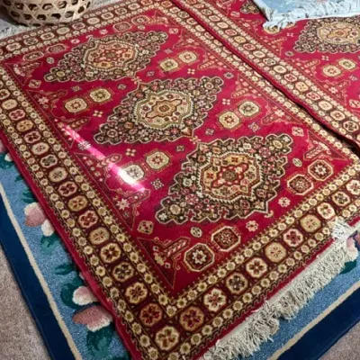Sale Photo Thumbnail #351: Traditional red area rug with intricate central medallions, geometric borders, and white fringe, layered over a blue floral accent rug.