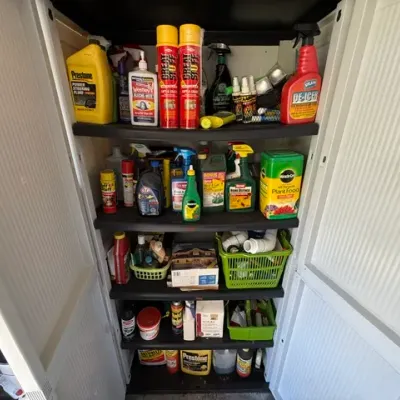 Sale Photo Thumbnail #483: Plastic storage cabinet filled with assorted household, automotive, and garden chemicals, including power steering fluid, plant food, and spray cleaners.