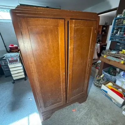 Sale Photo Thumbnail #368: Vintage Art Deco wooden wardrobe cabinet with double doors and a stepped top, showing light wear and scuffing to the finish.