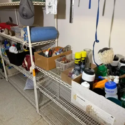 Sale Photo Thumbnail #384: Wire shelving units holding various household supplies, cleaning products, water bottles, and storage boxes.