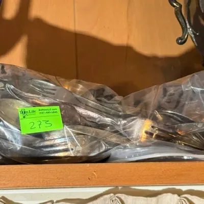 Sale Photo Thumbnail #269: Assorted silver-plated flatware pieces stored in clear plastic bags, including spoons and forks with vintage ornamental handles.