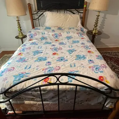 Sale Photo Thumbnail #294: Twin bed frame featuring wrought iron scrolling detail with wooden corner posts, flanked by a pair of brass brass-style table lamps on round wooden nightstands.
