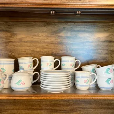 Sale Photo Thumbnail #13: Pfaltzgraff Tea Rose pattern ceramic tableware set, including mugs, teacups, saucers, creamer, sugar bowl, and utensil jar displayed on a wooden shelf.