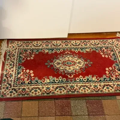 Sale Photo Thumbnail #167: Small Oriental-style accent rug featuring a central medallion and ornate border in red, cream, and teal with fringe edges.