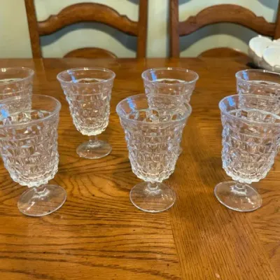 Sale Photo Thumbnail #25: Set of seven vintage clear pressed glass goblets featuring a textured diamond pattern, displayed on a wooden table.