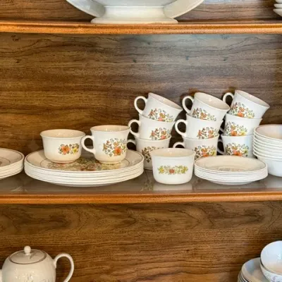 Sale Photo Thumbnail #16: Vintage Corelle Pyrex dinnerware set in floral pattern displayed on wooden hutch shelves, including teacups, saucers, and bowls.