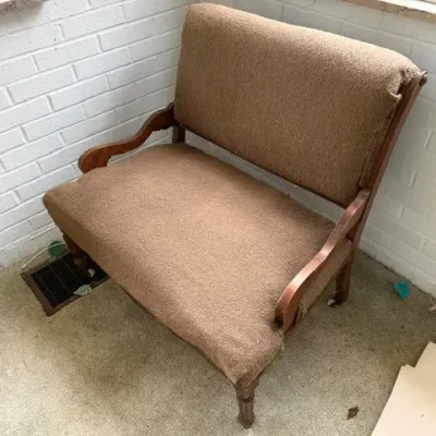 Sale Photo Thumbnail #196: Vintage wide armchair or settee featuring a dark wood frame with curved armrests and textured brown upholstery.