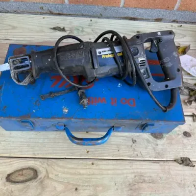Sale Photo Thumbnail #204: Vintage Black & Decker Professional Cut-Saw corded reciprocating saw resting on a blue metal Skil tool box.