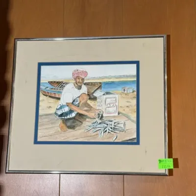 Sale Photo Thumbnail #130: Framed original watercolor painting depicting a fisherman with his catch on a beach, presented in a chrome frame with double matting.