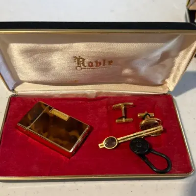 Sale Photo Thumbnail #227: Vintage Noble gold-tone and faux tortoiseshell men's gift set, including a cigarette lighter, cufflinks, and a tie bar presented in its original satin-lined case.