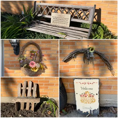 Sale Photo Thumbnail #492: Collection of outdoor and garden decor, including a weathered wooden garden bench with a memorial plaque, a rustic wooden chair planter, floral twig wreaths, and a slate 'Welcome Friends' sign.
