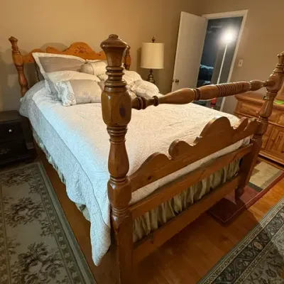 Sale Photo Thumbnail #144: Traditional pine four-poster bed frame dressed in light bedding, flanked by nightstands with table lamps.