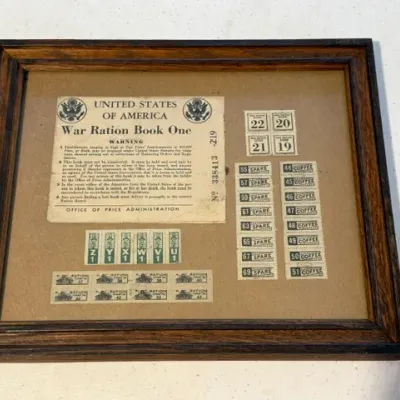 Sale Photo Thumbnail #215: Framed WWII-era United States of America War Ration Book One cover and assorted ration stamps in a dark wood frame.