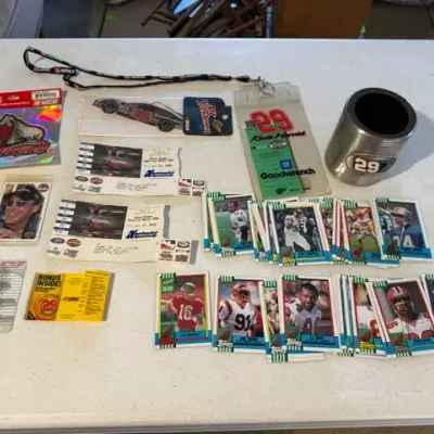 Sale Photo Thumbnail #216: Collection of Kevin Harvick NASCAR memorabilia alongside vintage football trading cards, including lanyards, decals, and a can cooler.