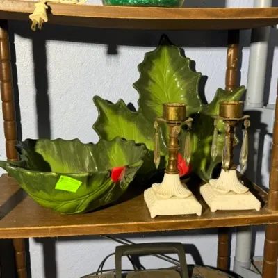 Sale Photo Thumbnail #400: Vintage ceramic holly leaf bowl and matching platter alongside a pair of brass and glass crystal candlestick holders displayed on a wooden shelf.