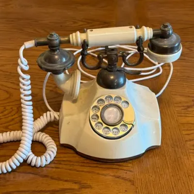 Sale Photo Thumbnail #18: Vintage French-style rotary desk phone featuring off-white plastic casing with brass accents and a coiled cord.
