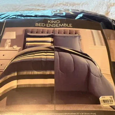 Sale Photo Thumbnail #152: 8-piece king-size bed ensemble in original clear plastic packaging, featuring a reversible striped comforter and matching shams.
