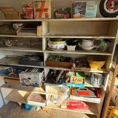 Sale Photo Thumbnail #480: Large wooden workshop shelving unit filled with vintage tools, dishware, household hardware, and various estate sale items.