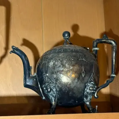 Sale Photo Thumbnail #271: Antique silver-plated teapot featuring heavily tarnished metal, ornate engraved patterns, and lion-head feet.