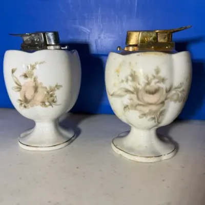 Sale Photo Thumbnail #51: Pair of vintage porcelain table lighters featuring floral motifs, silver-toned and gold-toned inserts, and pedestal bases.