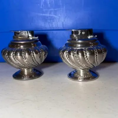 Sale Photo Thumbnail #52: Pair of vintage silver-plated table lighters featuring a spiral gadrooned design on pedestal bases.