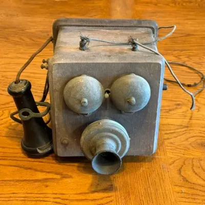 Sale Photo Thumbnail #21: Antique wooden box hand-crank telephone featuring twin metal ringer bells, a mouthpiece, and a detached earpiece receiver.