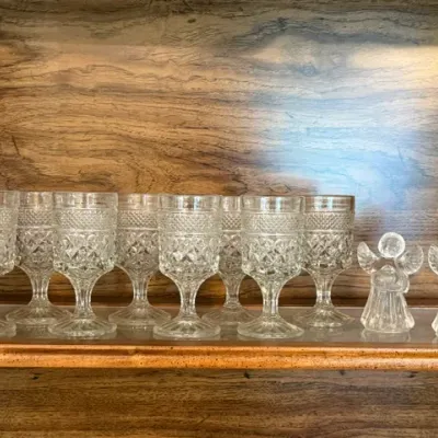Sale Photo Thumbnail #14: Set of eight clear pressed-glass wine goblets featuring a diamond pattern, alongside two small glass angel figurines.