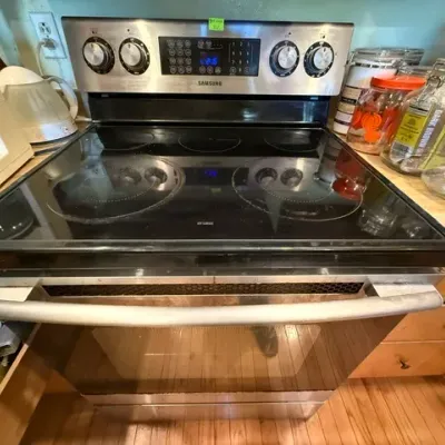 Sale Photo Thumbnail #300: Modern Samsung stainless steel electric range featuring a black glass smooth cooktop and digital control panel.