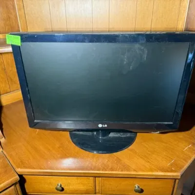 Sale Photo Thumbnail #288: Black LG flat-screen LCD monitor with an oval base, sitting on a wooden hutch desk.