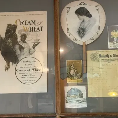 Sale Photo Thumbnail #303: Framed collection of vintage ephemera including an early 20th-century Cream of Wheat advertisement, a hand fan with a portrait, trade cards, and a Smith & Son billhead.