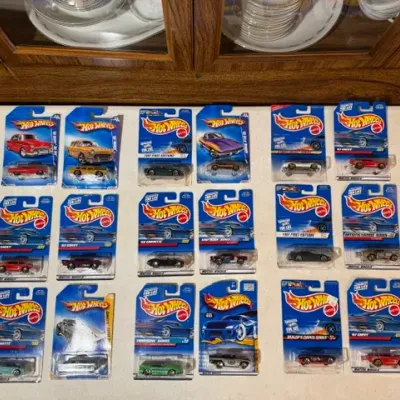 Sale Photo Thumbnail #86: Collection of 18 vintage packaged Hot Wheels die-cast cars from the 1990s displayed on a counter.