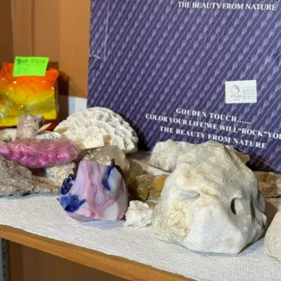 Sale Photo Thumbnail #121: Collection of various minerals, rough stones, slag glass chunks, and coral specimens displayed on a wooden shelf.