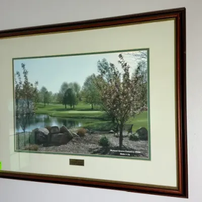 Sale Photo Thumbnail #141: Framed color photograph of Walnut Grove Country Club Hole #13, featuring a lake, cherry blossom trees, and a wooden bench in a mahogany-toned frame with gold trim.