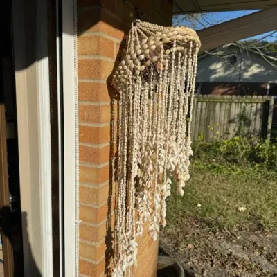 Sale Photo Thumbnail #479: Vintage boho hanging seashell light fixture or wind chime featuring a woven shell canopy and long cascading strands of small white shells.