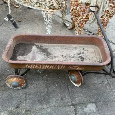 Sale Photo Thumbnail #495: Vintage Greyhound Ball Bearing red metal coaster wagon featuring heavy surface rust, weathered paint, and original stencil lettering.