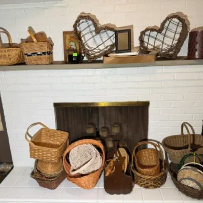 Sale Photo Thumbnail #341: Collection of assorted woven baskets in various shapes and sizes, displayed on and around a white brick fireplace hearth.