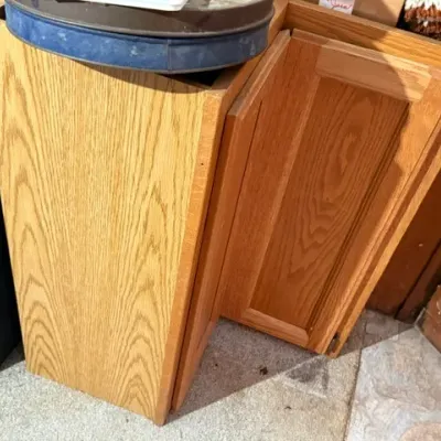 Sale Photo Thumbnail #371: Oak corner base cabinet with a bi-fold panel door and visible wood grain.