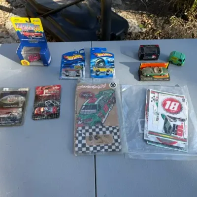 Sale Photo Thumbnail #478: Collection of vintage toy cars and NASCAR memorabilia, including packaged Hot Wheels, Thunder Jets slot car, Racing Champions die-cast vehicles, and Coca-Cola collectibles.