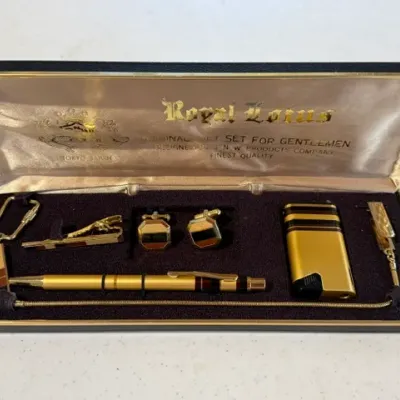 Sale Photo Thumbnail #229: Vintage Royal Lotus gentlemen's gift set in original presentation box, featuring a gold-tone lighter, pen, cufflinks, tie clip, and key chain.